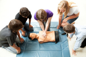 Teenage students use a mannequin to practice life saving techniques.